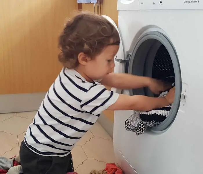 toddler loading up the washing machine