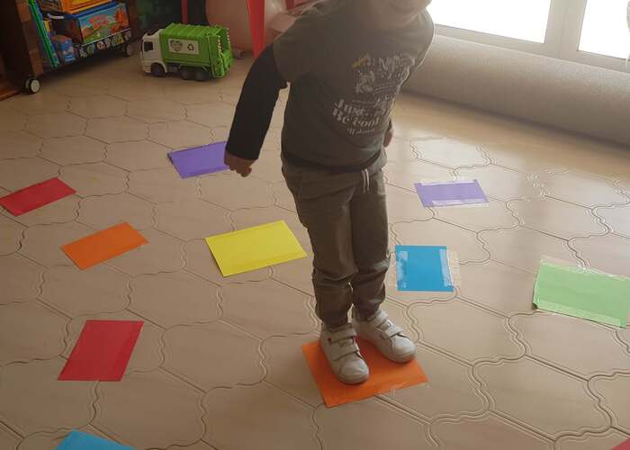 Child having fun while playing the coloured paper stepping stones game