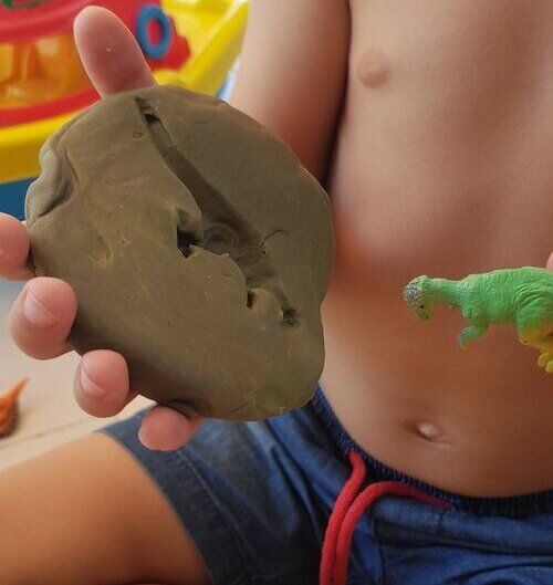 making a dinosaur impression in playdough